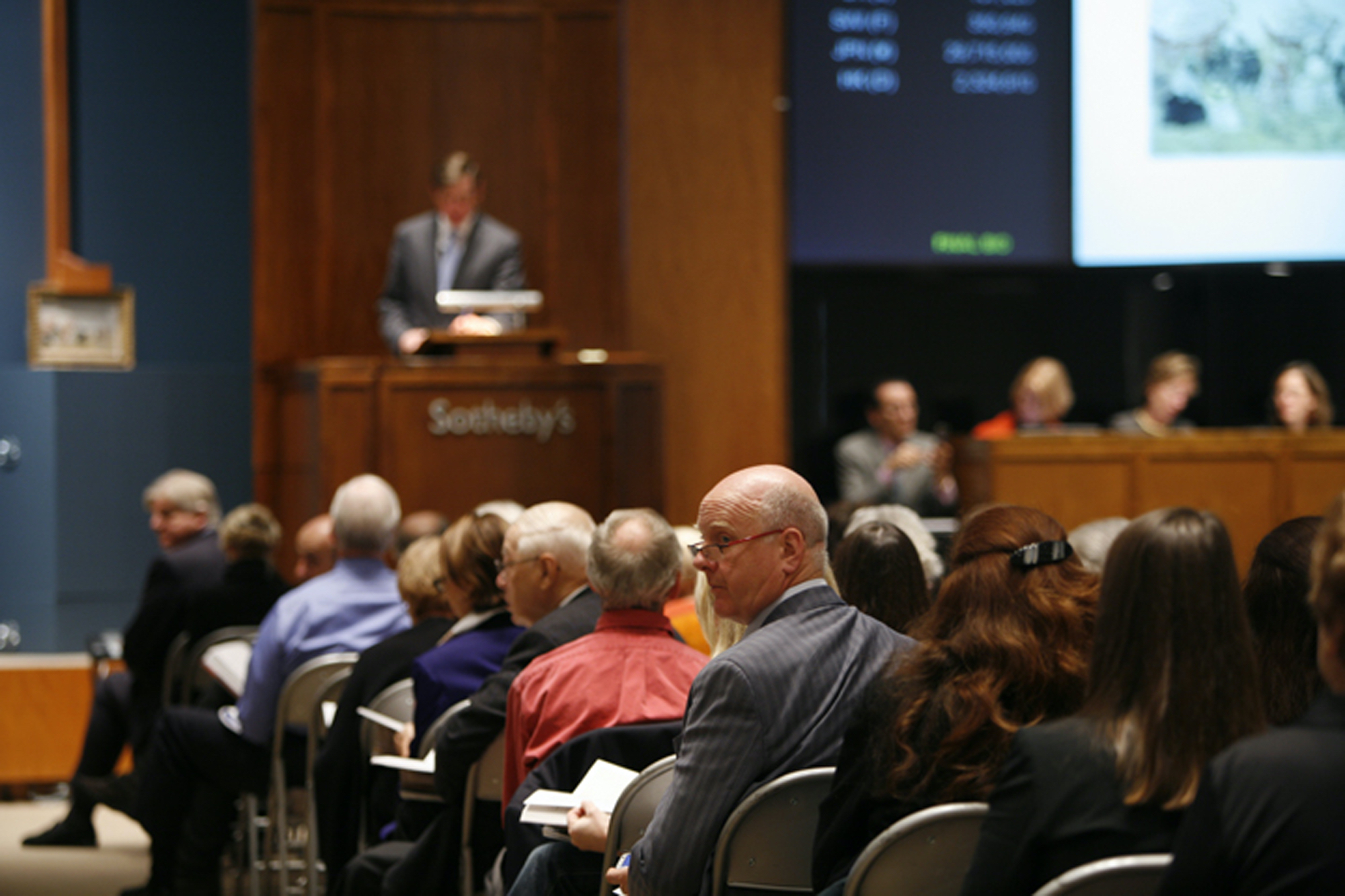 Ray Waterhouse seated at Sotheby's auction house in New York, glancing to the side as he holds a catalog