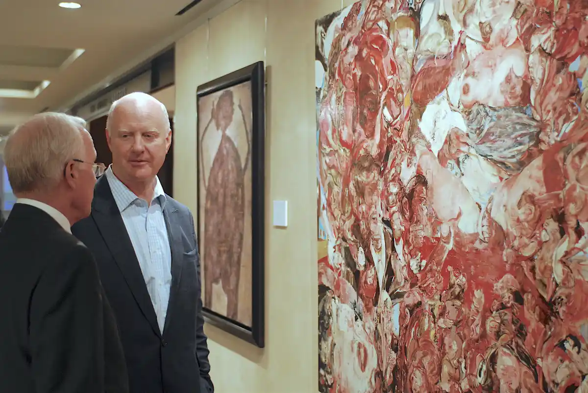Ray Waterhouse looking at and listening to a man in front of a painting. They are discussing how to invest in fine art.